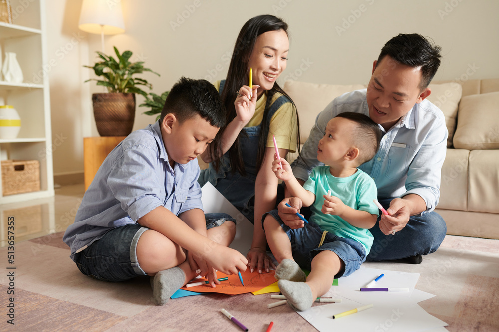 Joyful happy family of four drawing pictures together Joyful happy family of four drawing pictures together