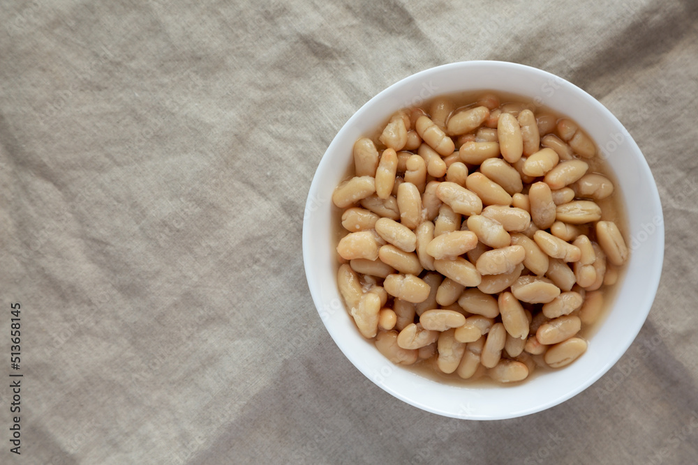 Organic White Cannellini Beans in a White Bowl, top view. Flat lay, overhead, from above. Space for text.