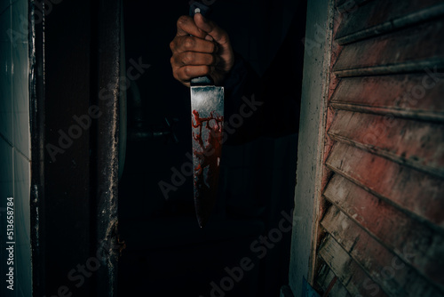 A male murderer holding a bloodstained knife that kills his victim in a very terrifying and terrifying way. photo