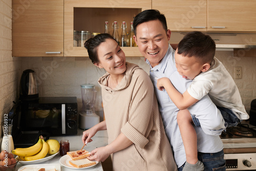 Little son suprising parents cooking jam toasts for dinner photo