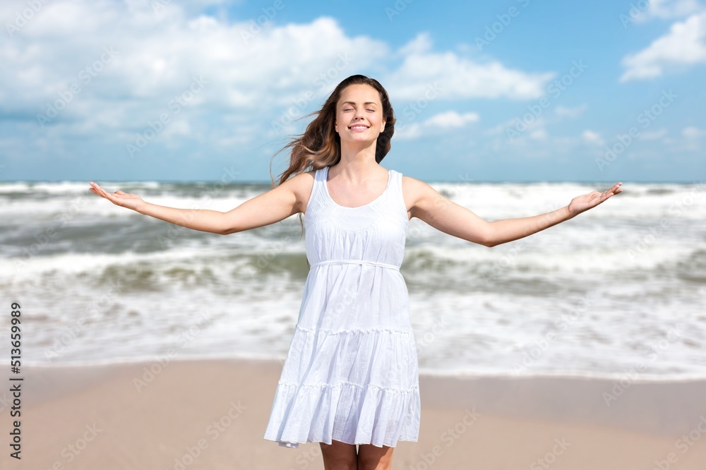 Smiling woman relaxing on beach background. Happy woman standing on the sun beach Smiling woman relaxing on beach background. Happy woman standing on the sun beach