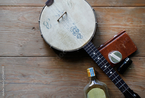Banjo, whiskey flask and leather book on wooden floorboards photo
