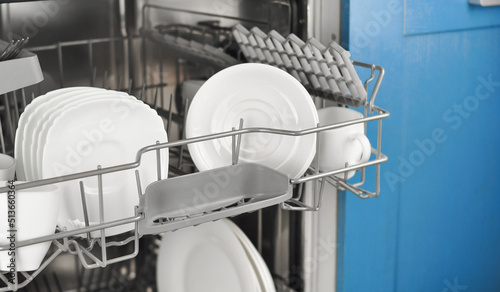 Dishwasher with white plates and cups on the kitchen