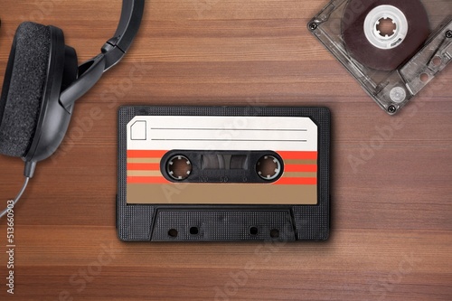 Vintage audio cassette between headphones and personal cassette player on a surface