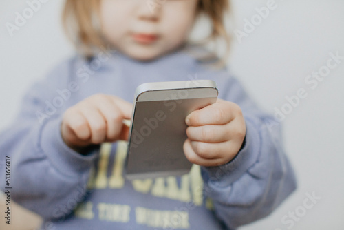 Little girl in violet hoodie using a phone on white background 