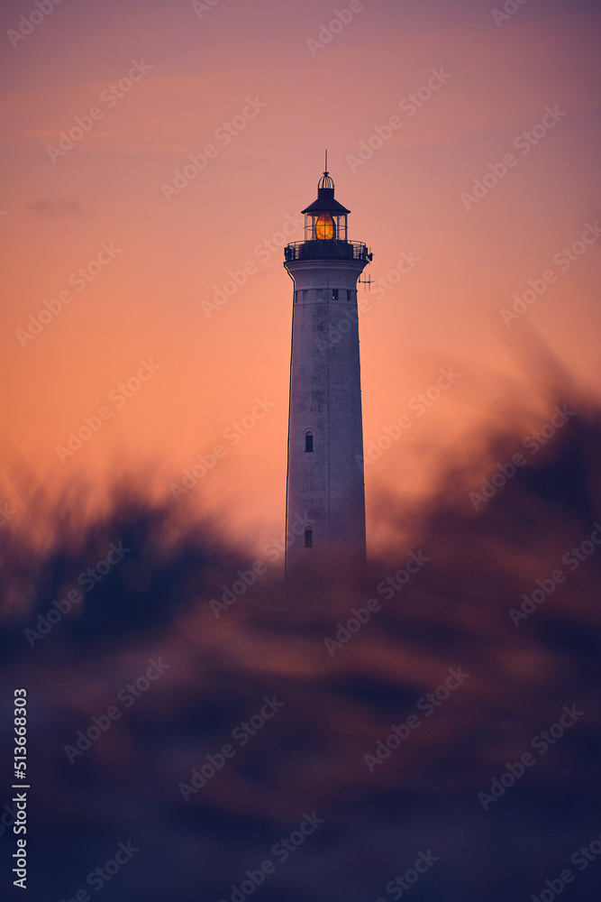 Lighthouse in warm morning sunlight behind the dunes. High quality photo