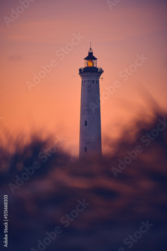 Lighthouse in warm morning sunlight behind the dunes. High quality photo