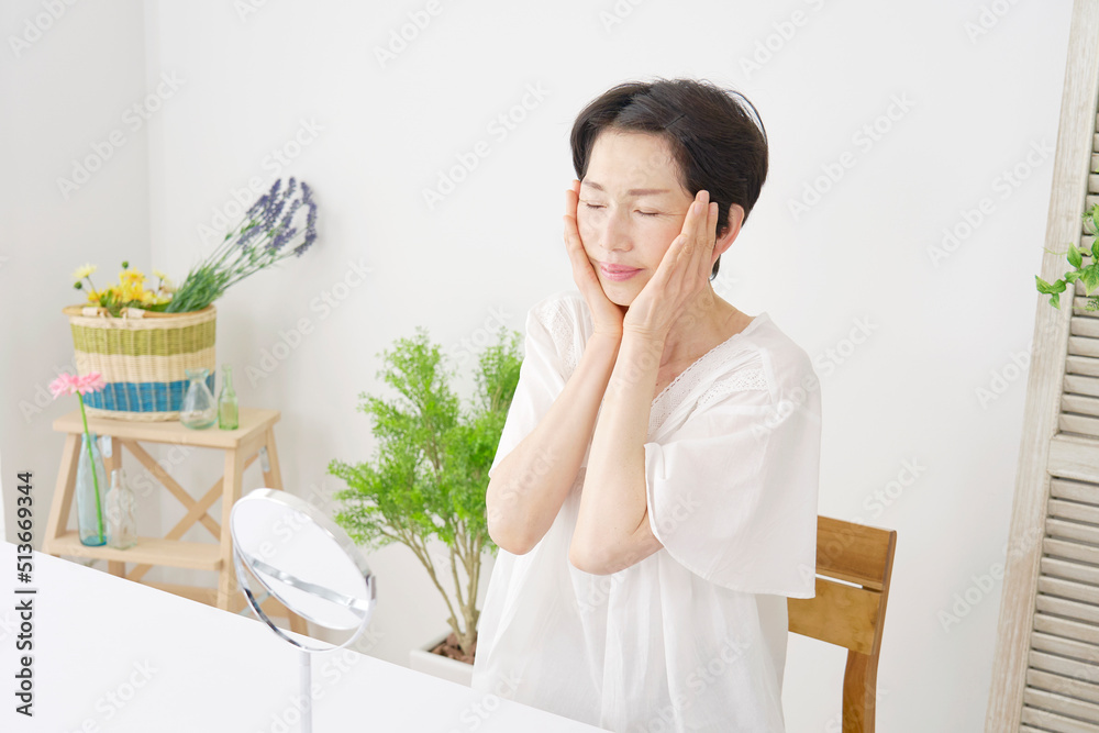 リビングでフェイシャルケアをする中年女性 リビングでフェイシャルケアをする中年女性