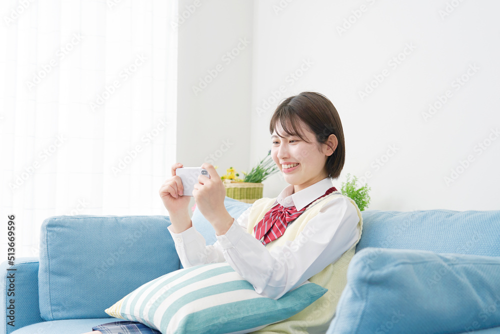 リビングでスマホを見る女子高生 リビングでスマホを見る女子高生