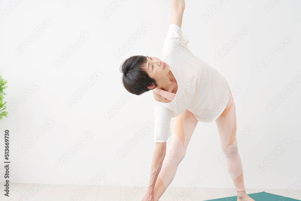 Naklejka premium 室内でヨガをする中年女性