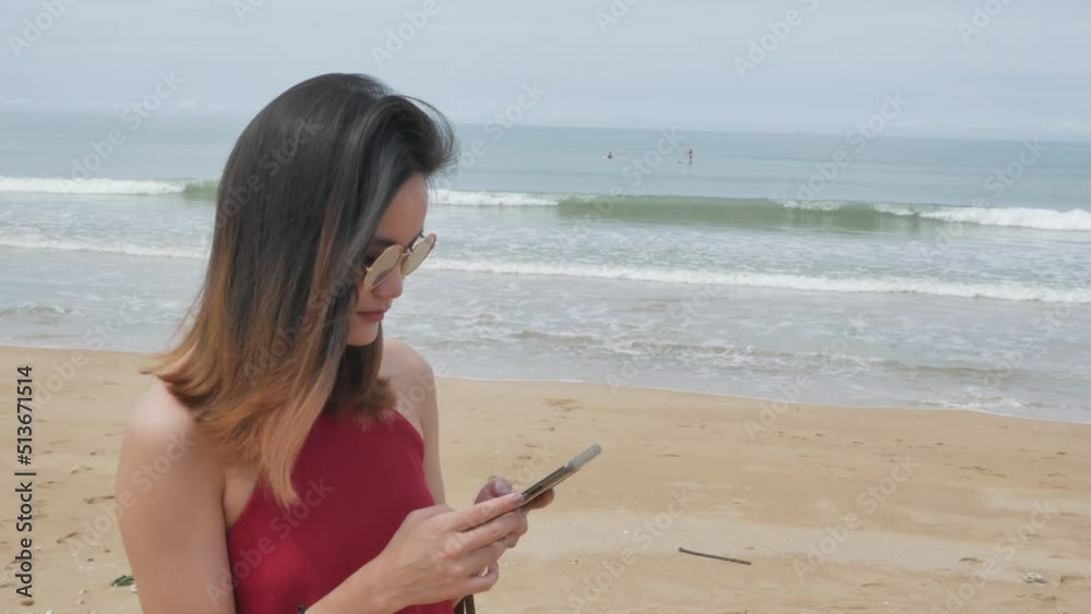 asian woman texting mobile phone while walking on the white sand beach in summer vacation holiday time. workcation concept. asian woman texting mobile phone while walking on the white sand beach in summer vacation holiday time. workcation concept.