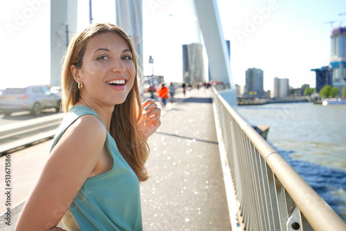 Portrait of lively girl turns around and smile to the camera with modern cityscape on the background, Rotterdam, Netherlands