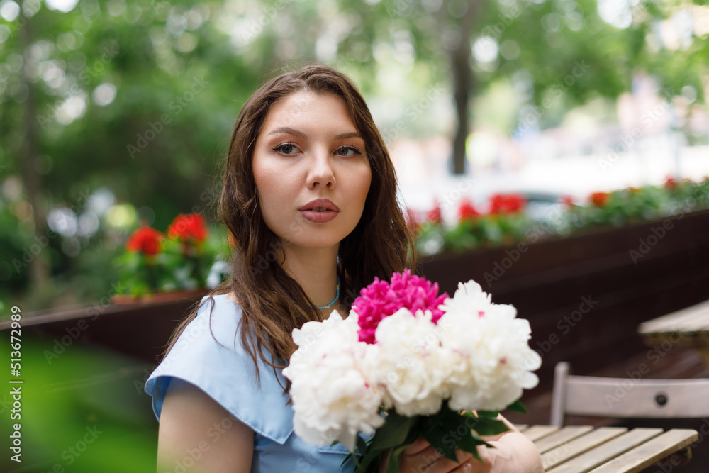 A beautiful young woman in a blue dress with a bouquet of peonies. A beautiful young woman in a blue dress with a bouquet of peonies.