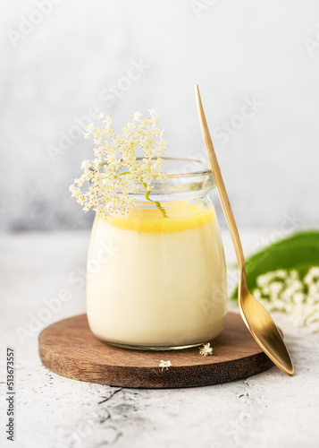 Homemade elder flower dessert panna cotta, mousse or pudding in a portion glass jar with lemon curd and fresh flowers. Copy space. photo