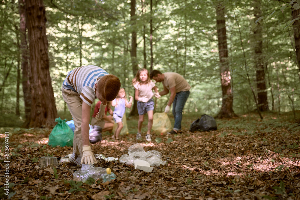 Ginger boy cleaning forest from trashes with family Ginger boy cleaning forest from trashes with family
