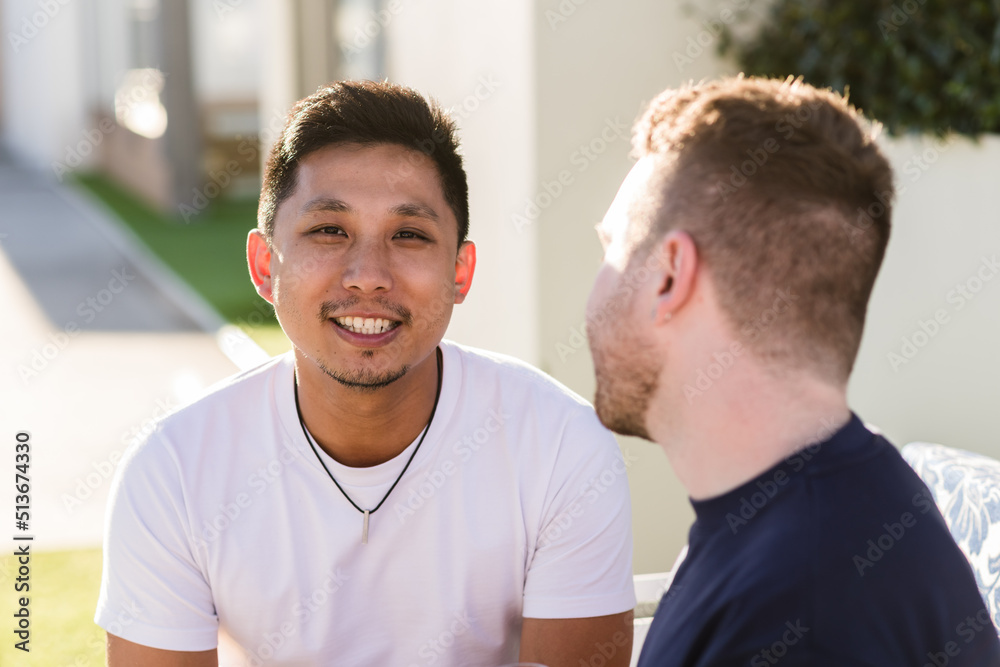 Gay couple sitting outside, mixed race Gay couple sitting outside, mixed race