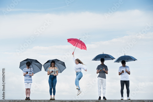 Teenager girl celebrating freedom from social media. Young woman holding red umbrella standing out from crowd. Overcoming digital addiction concept. photo