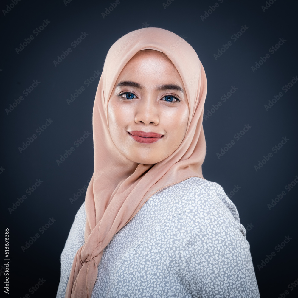 Close up portrait of a beautiful female model wearing traditional dress and hijab, a lifestyle apparel for Muslim women isolated on grey background. Idul Fitri and hijab fashion concept.