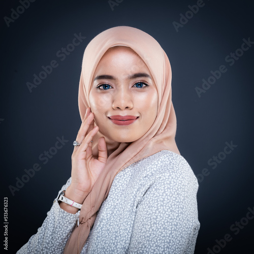Close up portrait of a beautiful female model wearing traditional dress and hijab, a lifestyle apparel for Muslim women isolated on grey background. Idul Fitri and hijab fashion concept.