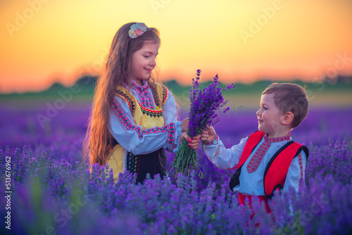Portrait of children boy and girl in traditional Bulgarian folklore costume in lavender field during sunset