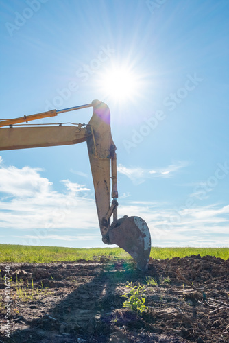 Excavator bucket on the background of a green field.