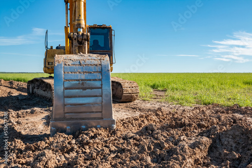 Excavator on the background of a green field. photo