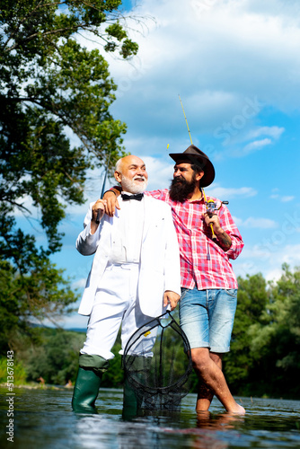 Men hobby and recreation. Fishermen successful catch fish. Fisher retirement. Retired businessman in suit with fishing rod. Male friendship. Granddad and drandson fishing. photo