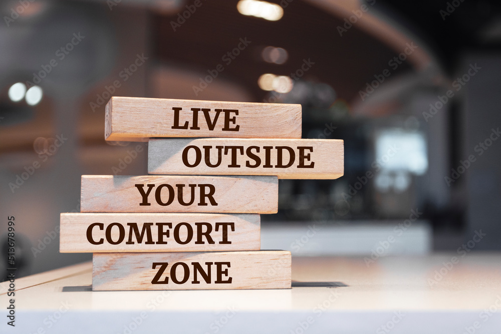 Wooden blocks with words 'Live outside your comfort zone'.