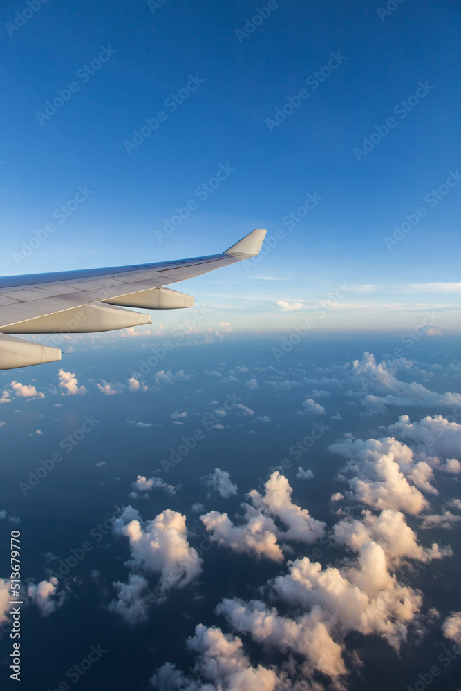 Fototapeta premium Fluffy clouds outside airplane window with view of airplane wing