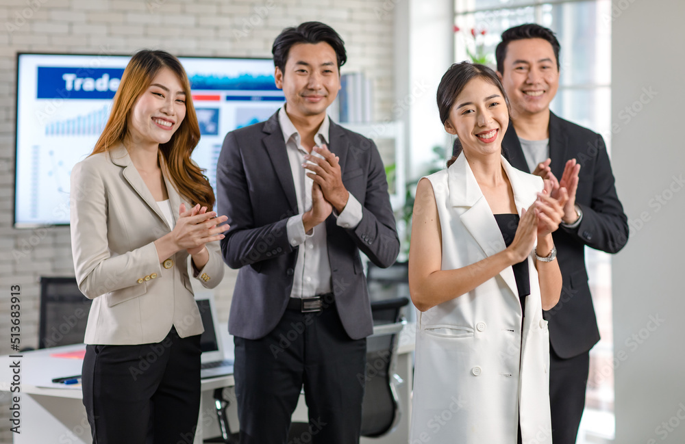 Obraz premium Group of Asian happy cheerful millennial professional successful male businessmen and female businesswomen in formal suit standing clapping hands applauding greeting celebrating together in office