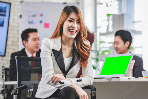 Portrait shot Asian young happy cheerful confident millennial professional successful female businesswoman in formal suit sitting crossed arms smiling while colleagues working in blurred background