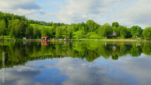 Blick   ber spiegelnden Bad Soier See mit gr  ner Landschaft und wei  en Wolken bei blauem Himmel