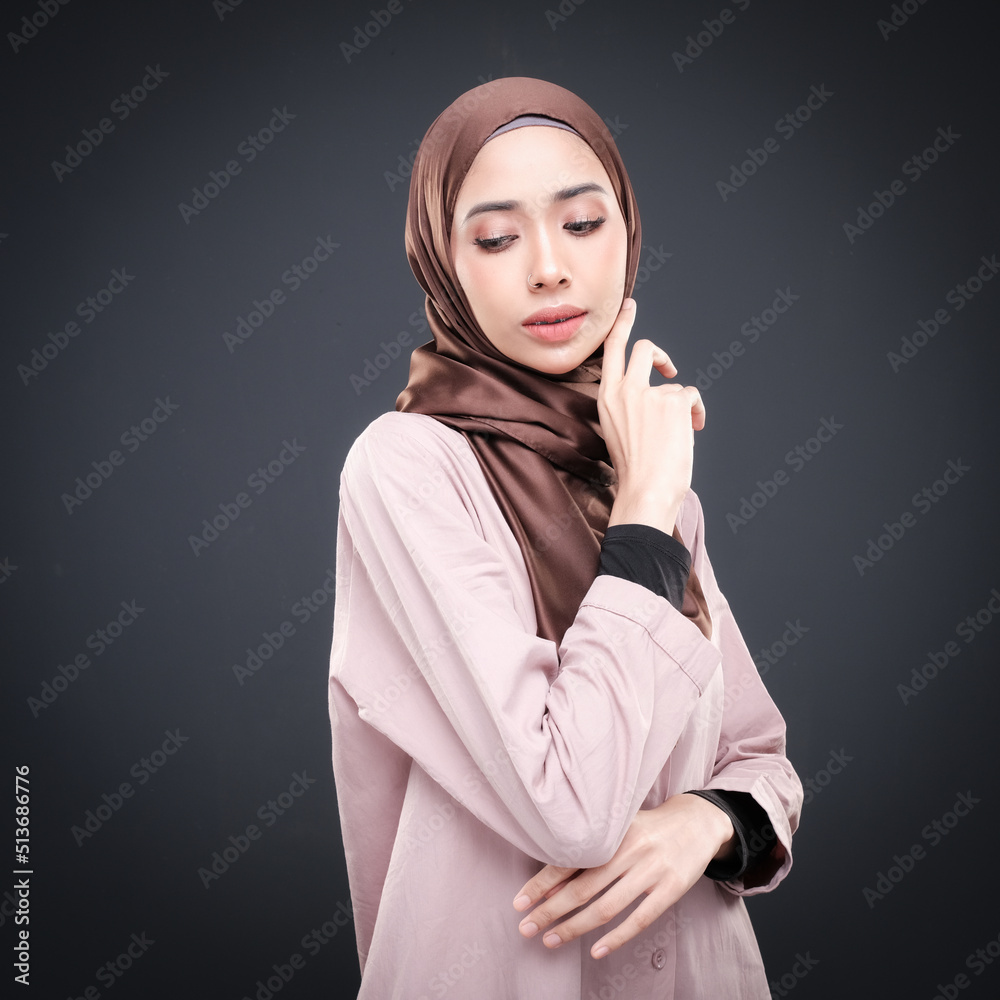 Half height portrait of a beautiful female model wearing traditional dress and hijab, a lifestyle apparel for Muslim women isolated on grey background. Idul Fitri and hijab fashion concept. Half height portrait of a beautiful female model wearing traditional dress and hijab, a lifestyle apparel for Muslim women isolated on grey background. Idul Fitri and hijab fashion concept.