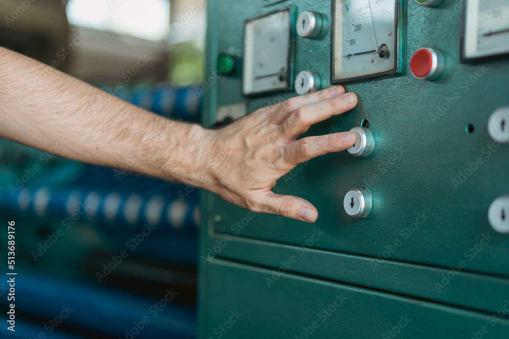 Obraz premium A close-up photo of a male hand holding a finger on a machine switch.