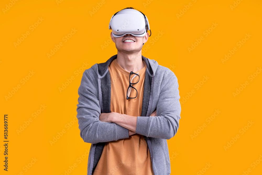 excited asian adult male wearing headset vr virtual goggle gadget in sport casual cloth playing sport online game with fun and joyful facial expression on yellow background studio portrait shot