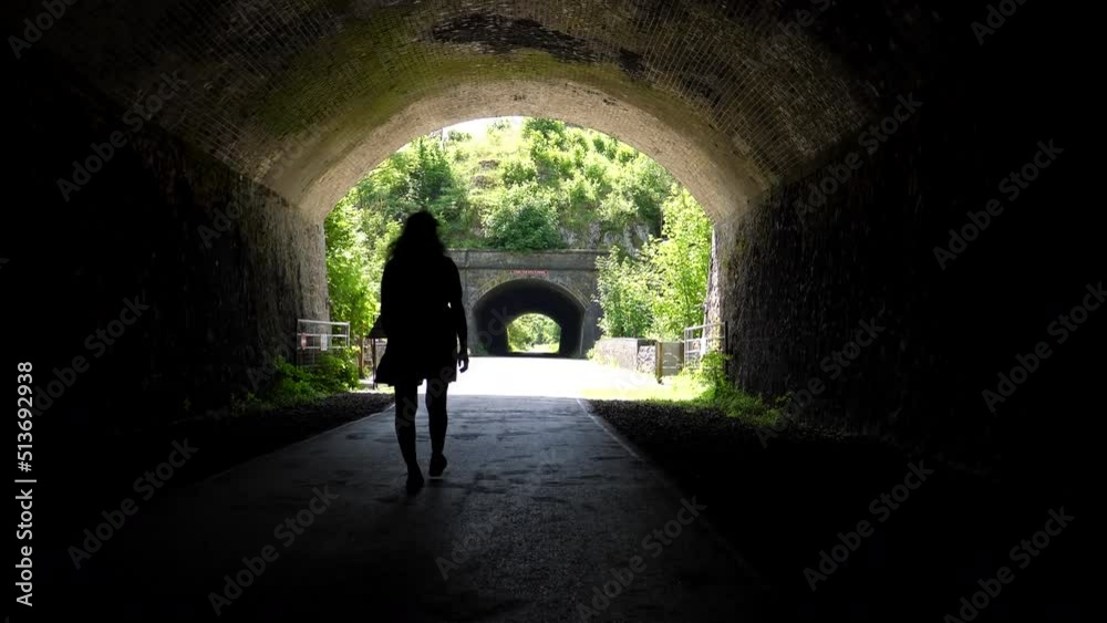 Rear view of unrecognizable woman walking through Chee Tor tunnels No1 and No2 on Monsal Trail in Peak District National Park. Rear view of unrecognizable woman walking through Chee Tor tunnels No1 and No2 on Monsal Trail in Peak District National Park.