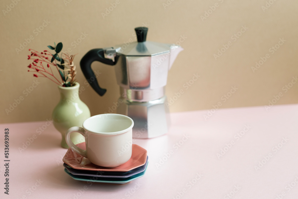Mocha coffee pot, cup, dry flowers on pink table. beige wall background