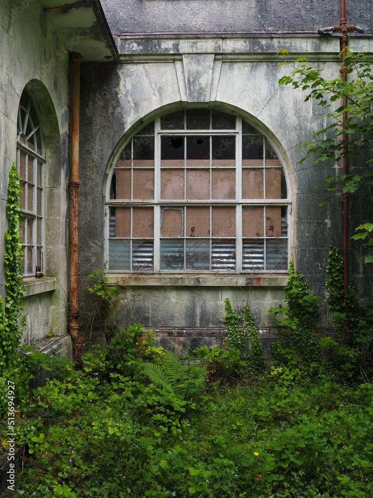 Abandoned secret garden with fancy rounded window with keystone in old building