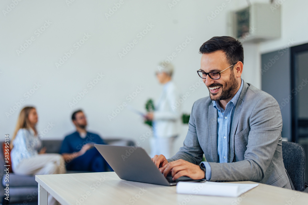 Smiling adult businessman working over the laptop at the office. Smiling adult businessman working over the laptop at the office.