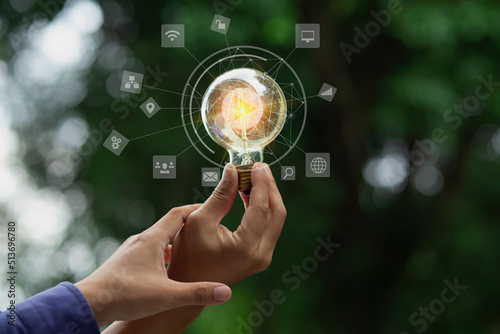 Quadro em tela Hand holding light bulb and sustainable development interface icons on green background, Technology and environment concept