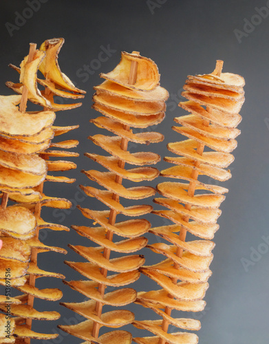Tornado potatoes chips - spiral french fries on wooden sticks, close-up. Twister potatoes on skewers, popular street food in Prague.