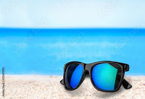 Sunglasses on beach sand with sea. The concept of a positive and successful holiday.