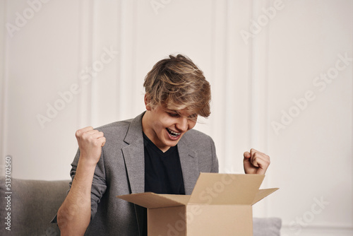 man sitting on the couch and unpacking cardboard box.