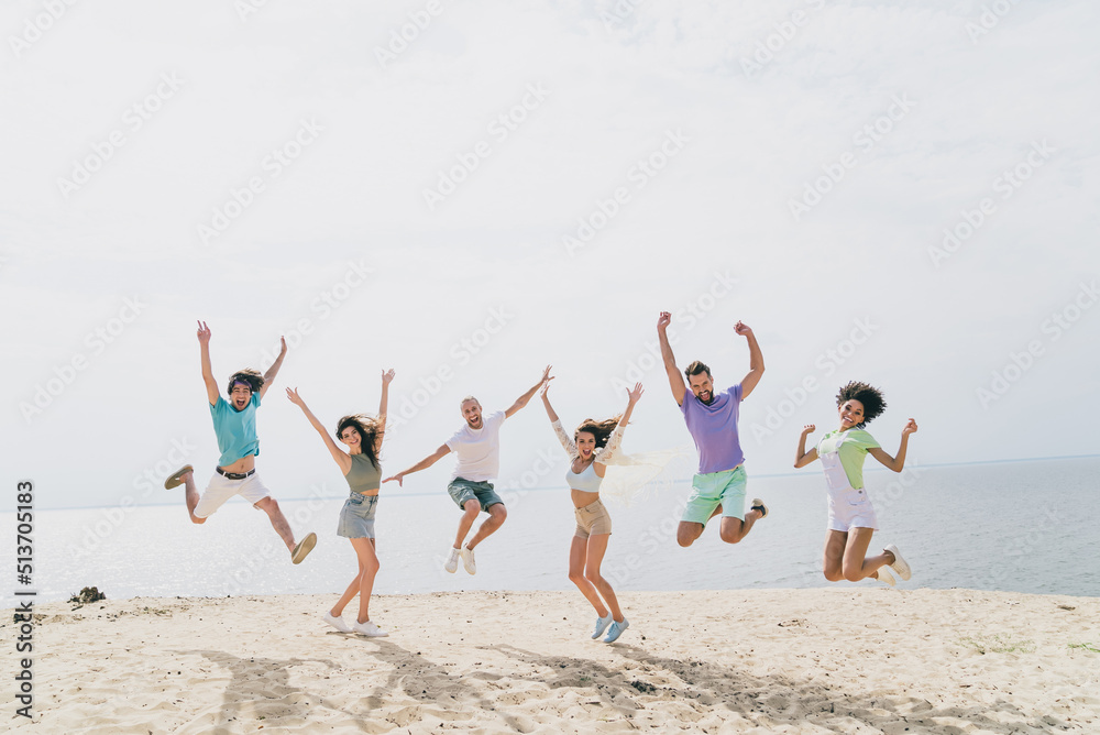 Full length photo of energetic carefree people have good mood jumping sand beach enjoy hang out outdoors