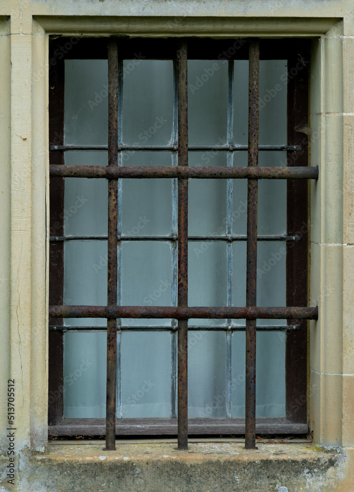 Barred window of a medieval building. Might be a prison or a bank vault.