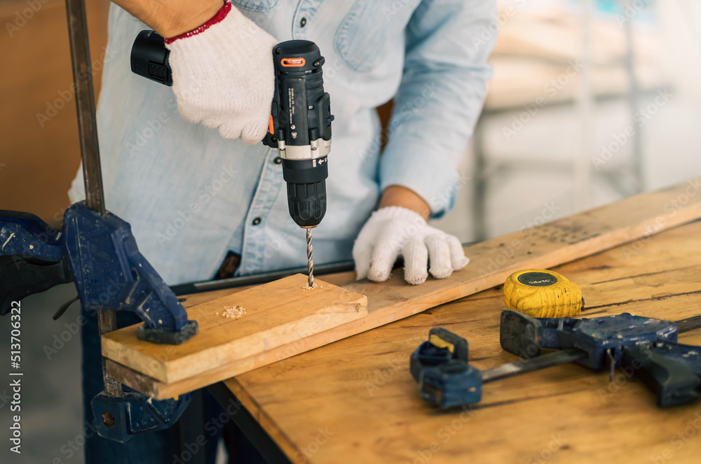 Choseup of carpenters working with electric drill in a carpentry workshop. Choseup of carpenters working with electric drill in a carpentry workshop.