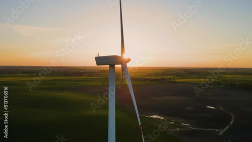 Close up windmill turbines or wind energy converter with rotating blades at sunset. Concept of electricity saving and alternative power source photo