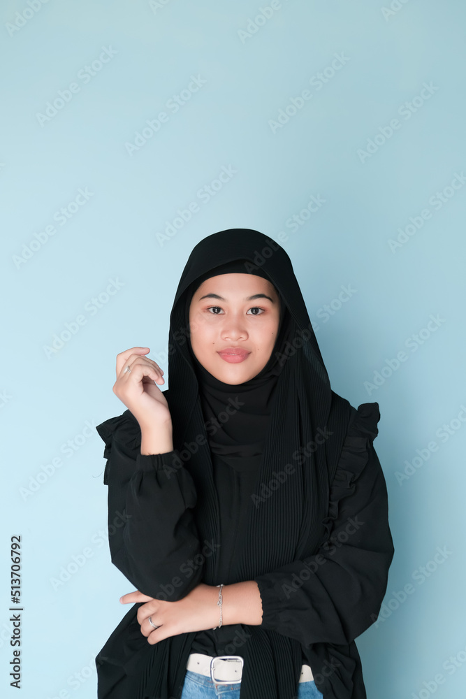 Expression of beautiful Asian girl in hijab in the black shirt on light blue background
Expression of beautiful Asian girl in hijab in the black shirt on light blue background
