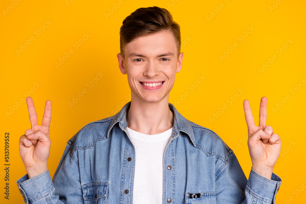 Photo of young cheerful man show fingers peace cool v-symbol journey isolated over yellow color background Photo of young cheerful man show fingers peace cool v-symbol journey isolated over yellow color background