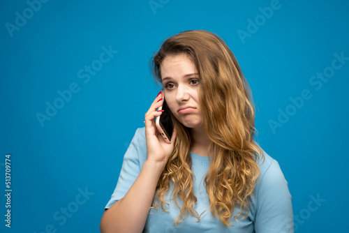 Young female feels displeased annoyed and anxious while speaking with a mobile phone.